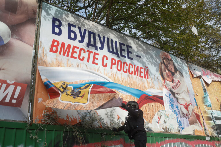 Ukraina politseinik eemaldamas Vene vägedelt tagasi vallutatud Hersonis Venemaa propagandaplakateid. Reuters/Scanpix 